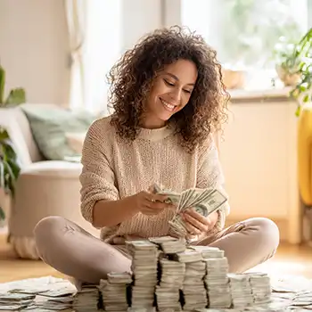Young woman smiling, counting a big stack of money